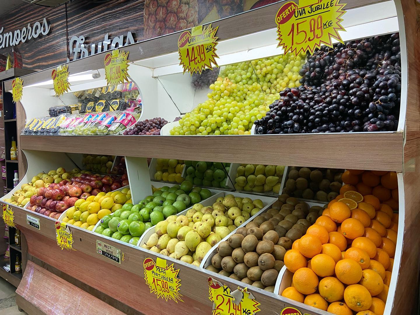Gôndola de frutas nobres com uvas, maçãs, peras e kiwis
